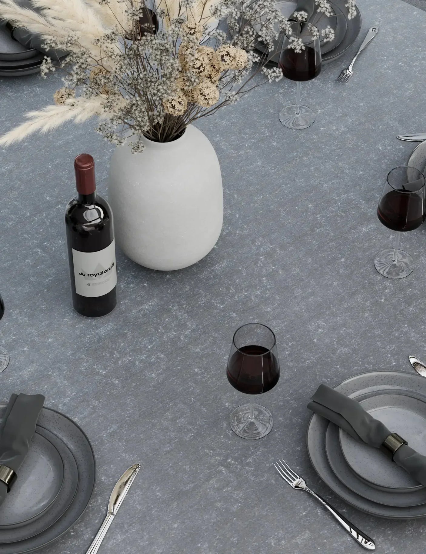 Grey stone dining table set with plates, cutlery, wine glasses, and ceramic vase centerpiece