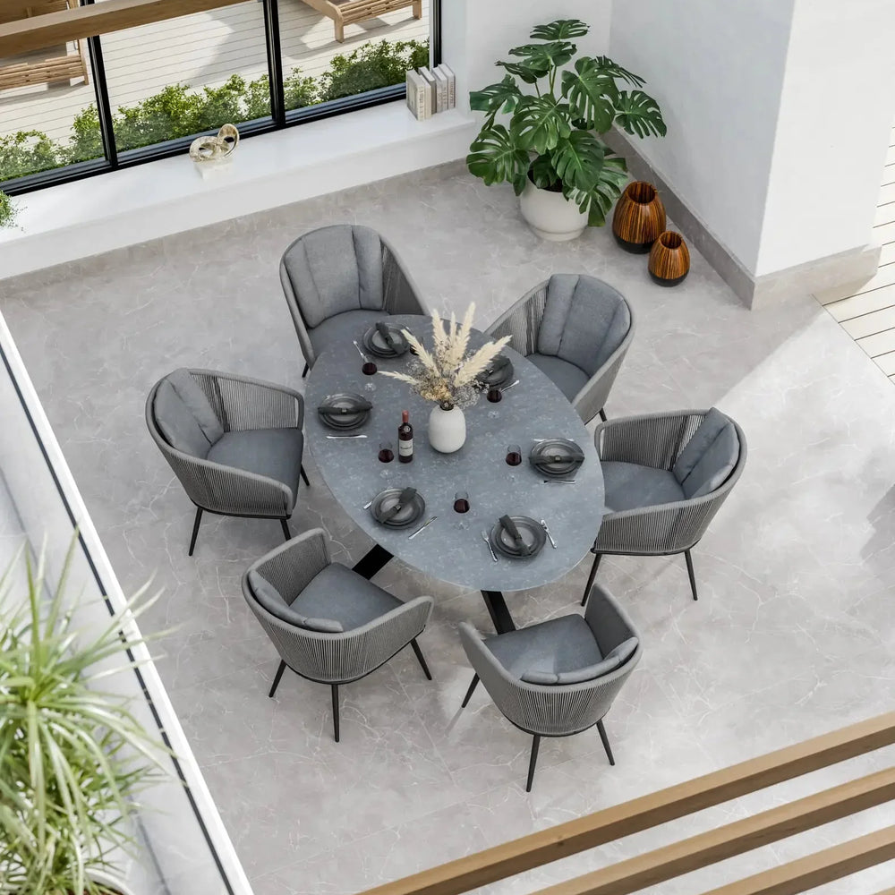 Grey oval dining table with six grey velvet chairs in modern bright dining room