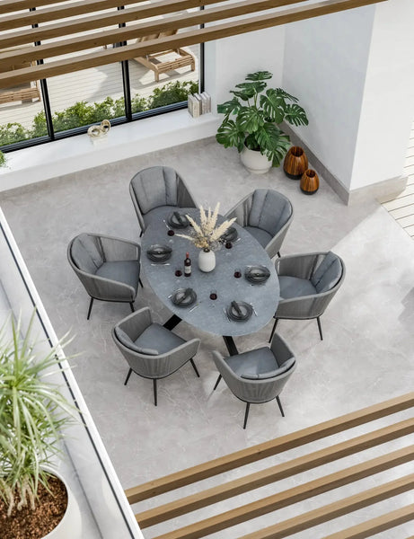 Grey oval dining table with six grey velvet chairs in modern bright dining room