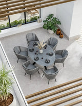 Grey oval dining table with six grey velvet chairs in modern bright dining room