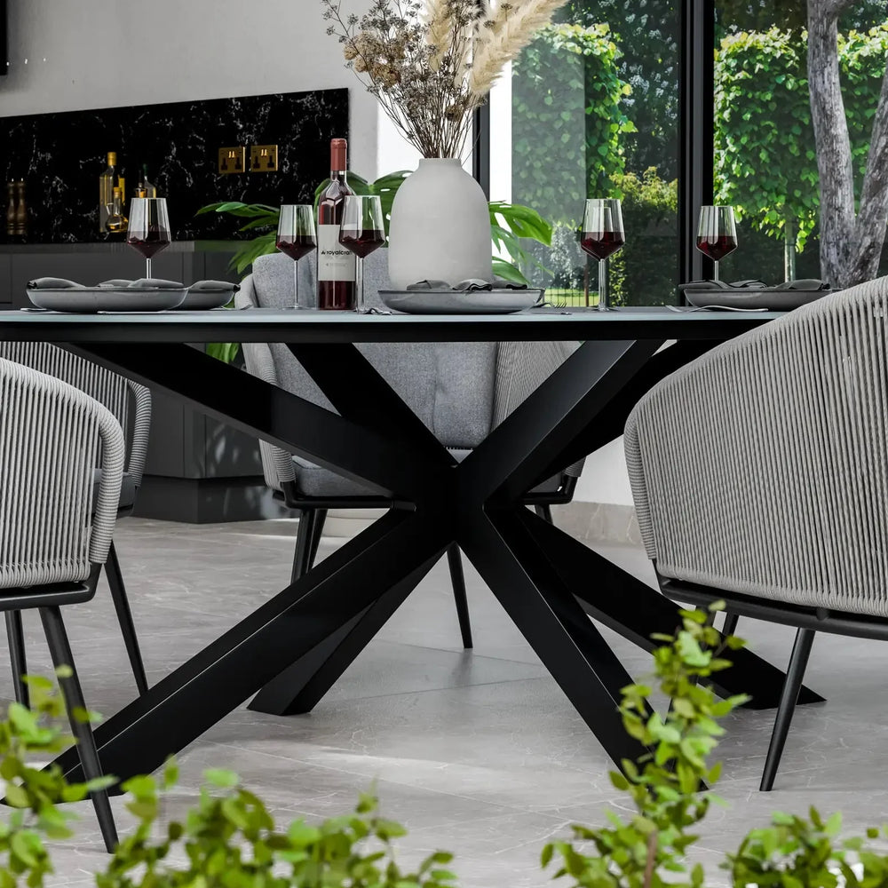 Black metal dining table with modern chairs, grey place settings and vase centerpiece