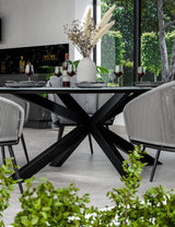 Black metal dining table with modern chairs, grey place settings and vase centerpiece