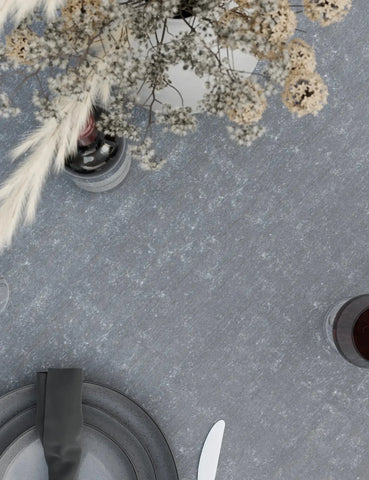Grey stone dining table with ceramic plates, black napkin, wine glass, and floral centerpiece