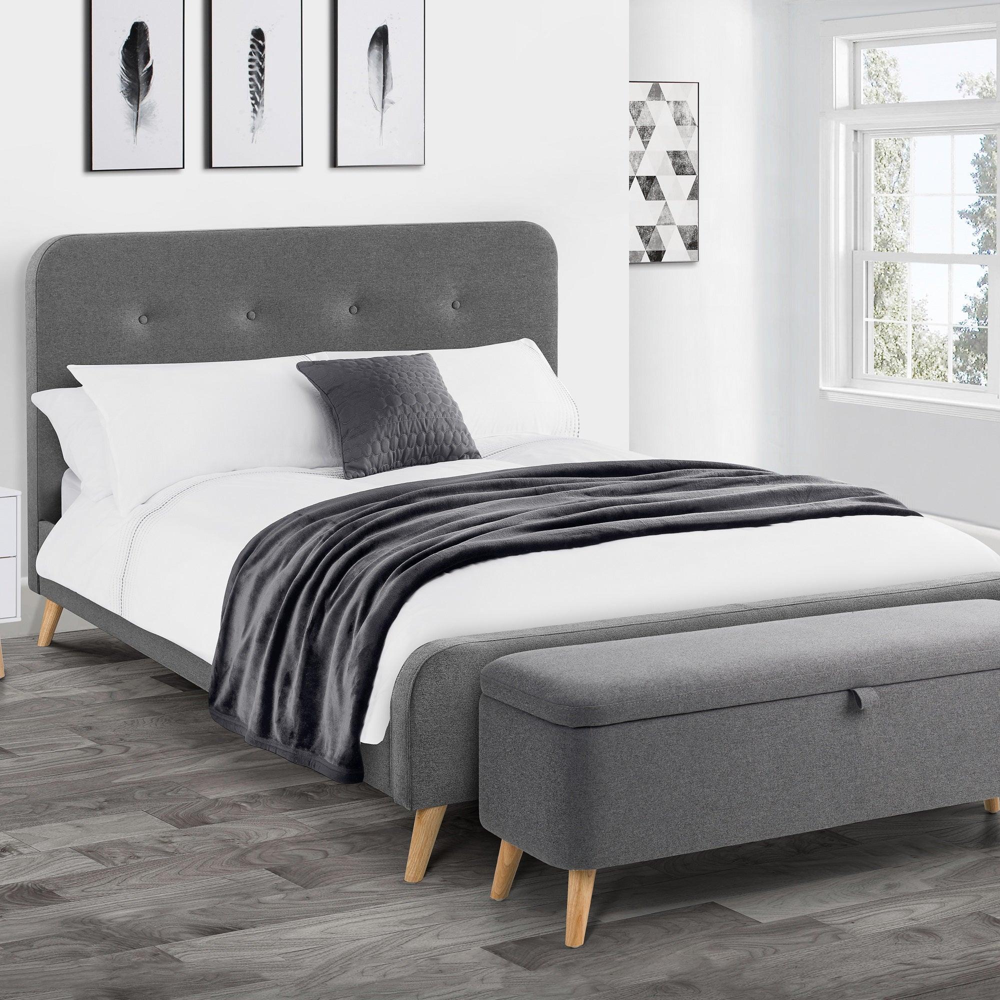 Grey linen double bed with buttoned headboard and matching storage bench in bright bedroom