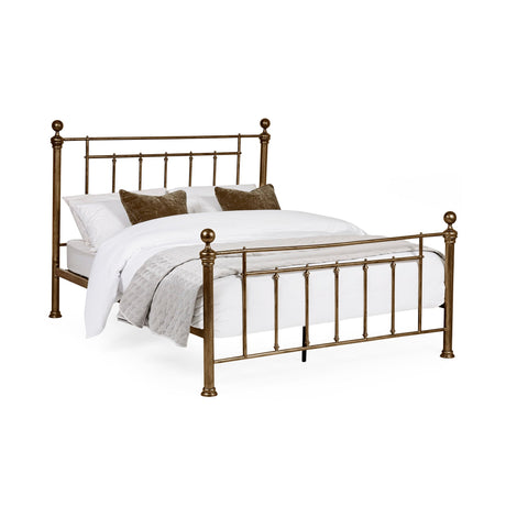 Gold metal bed with white bedding and gray quilt, viewed angled on white background