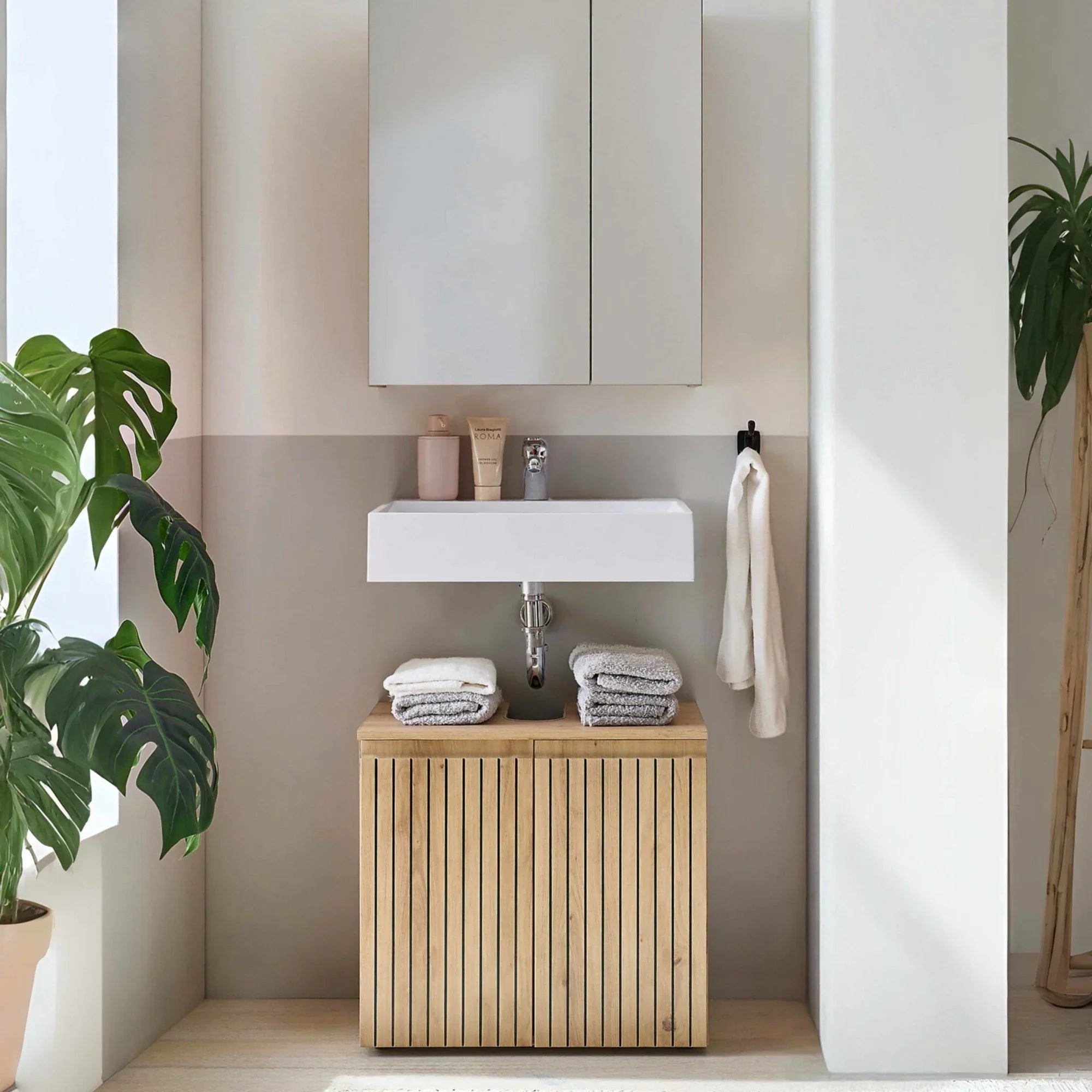 Modern bathroom vanity unit with wooden slatted cabinet and white basin, stacked towels