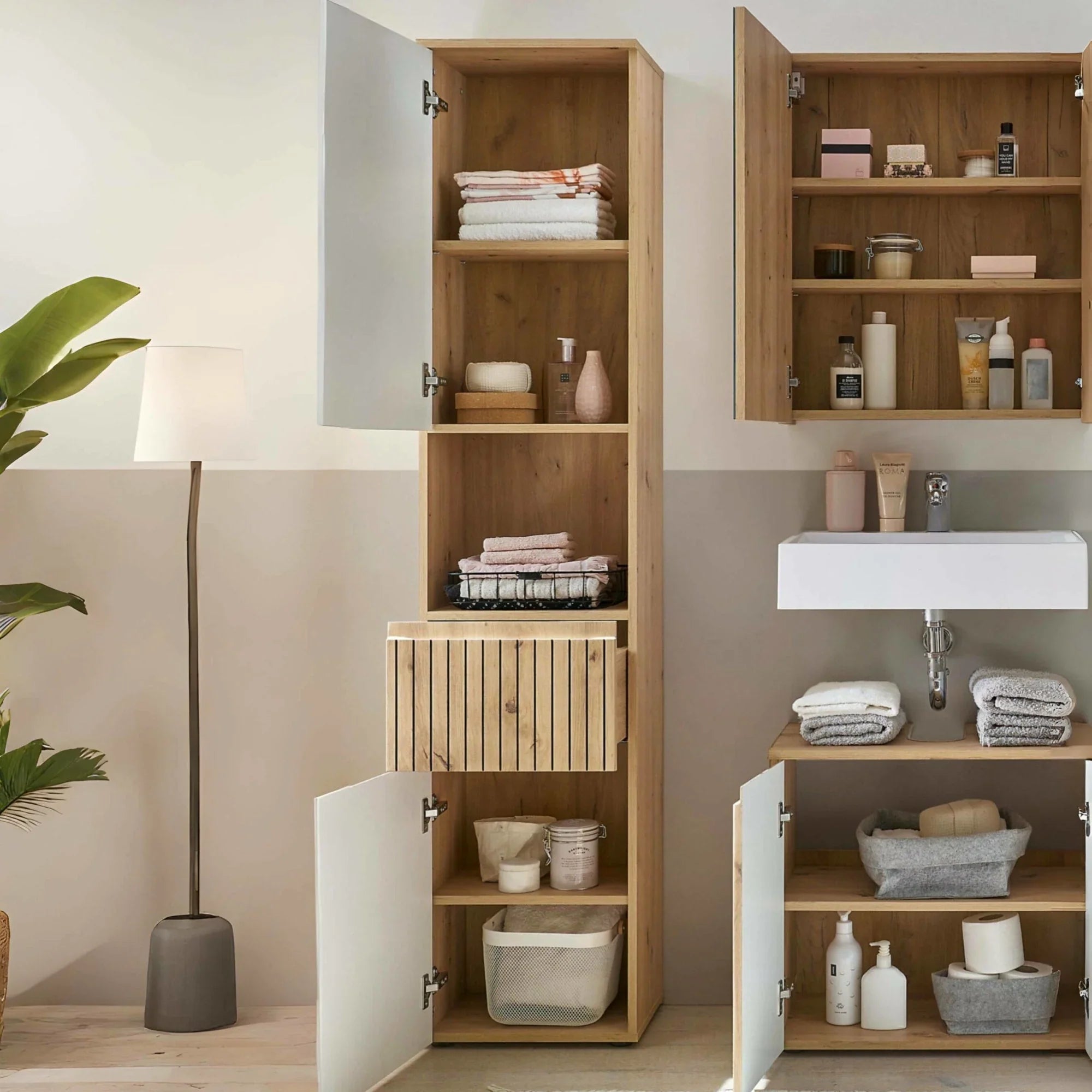 Tall wood bathroom storage unit with open shelves and cabinets, organized with towels and baskets