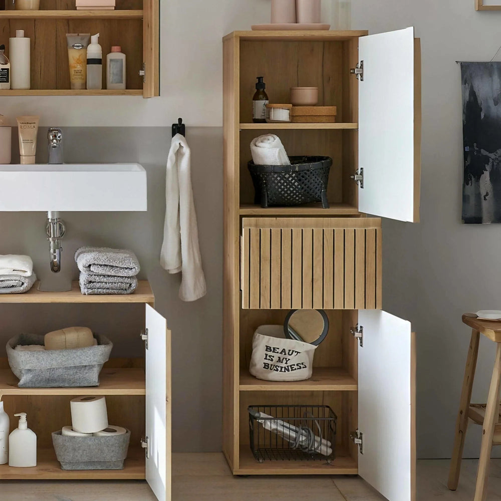 Tall oak bathroom storage cabinet with white doors and open shelves, filled with towels