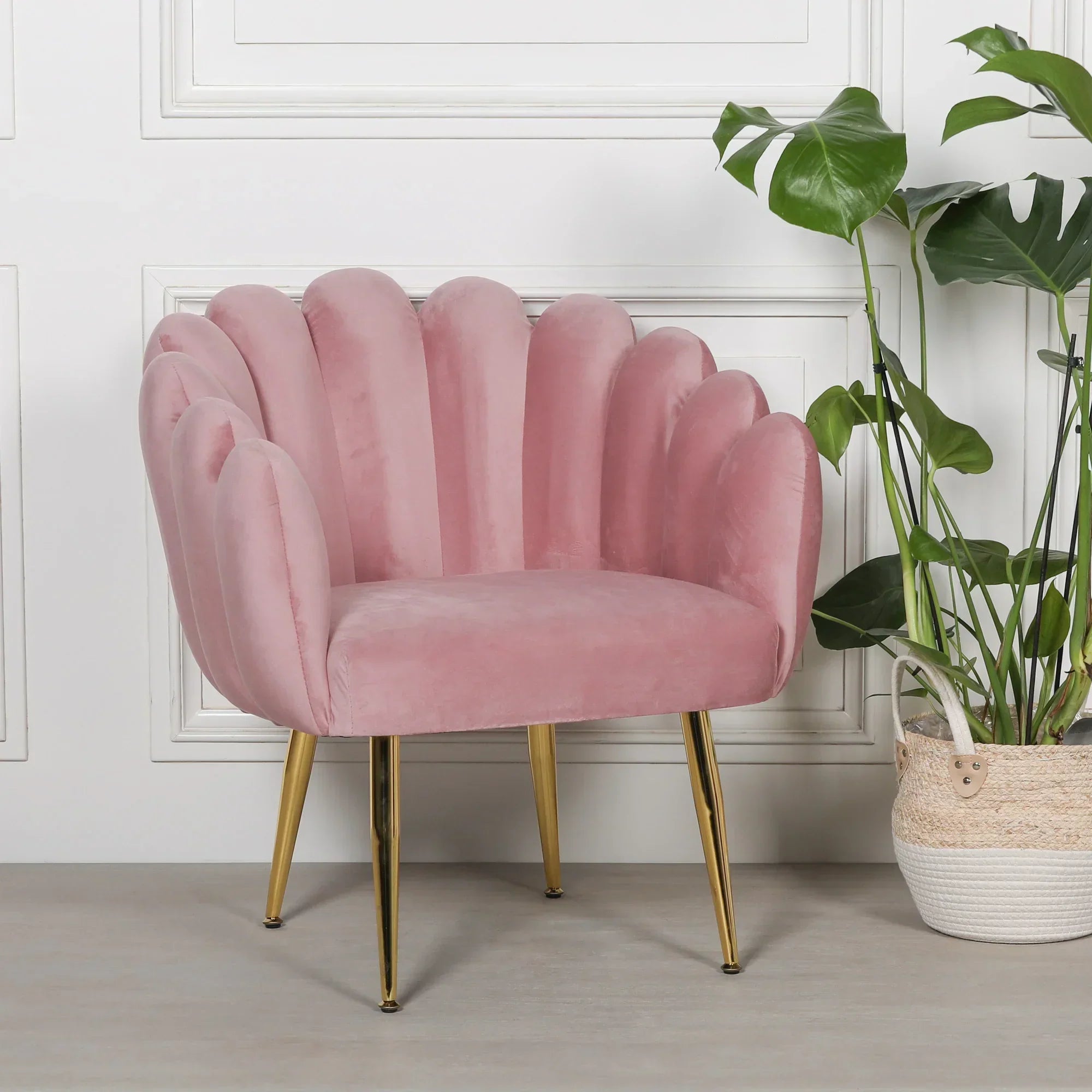 Pink velvet accent chair with gold legs beside potted plant in modern living room