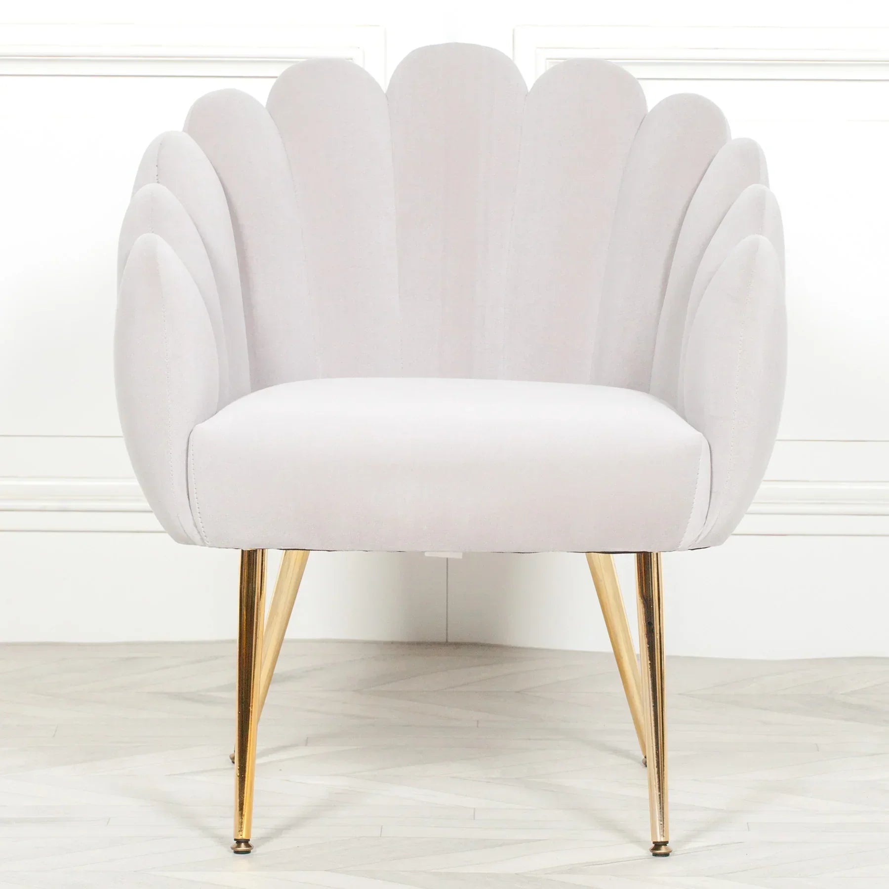 Light grey scallop accent chair with gold legs on wooden floor