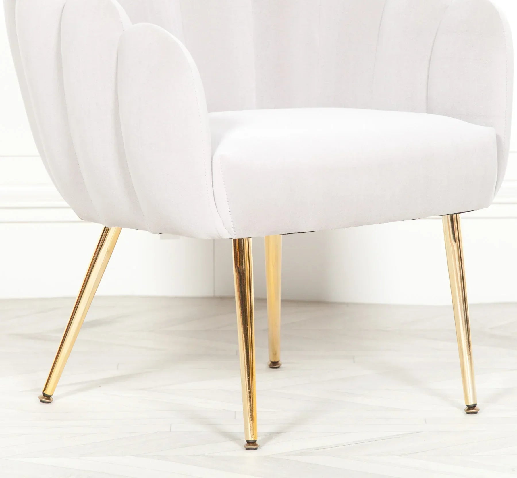 White velvet accent chair with gold metal legs on herringbone floor