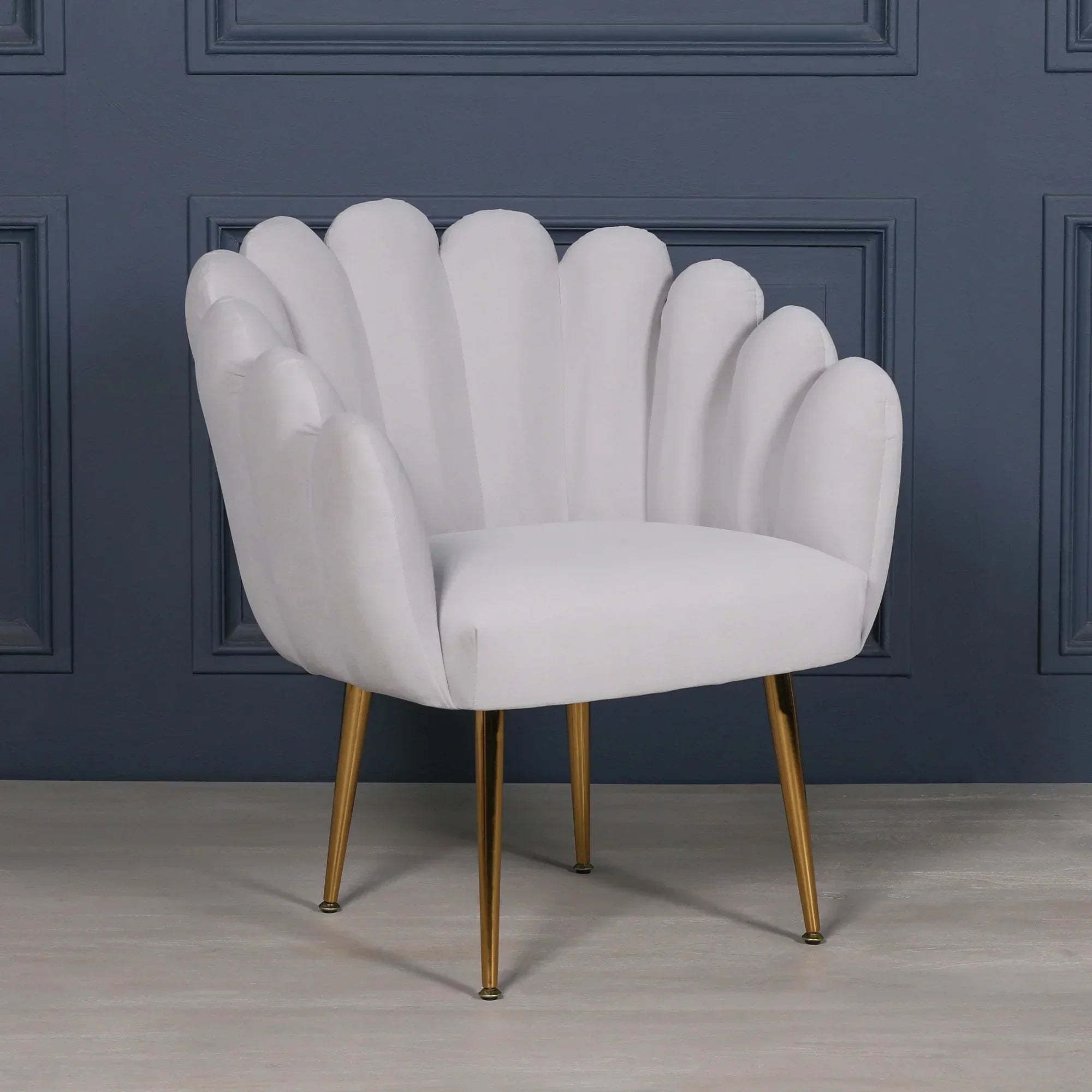 White scalloped accent chair with gold legs against blue panel wall