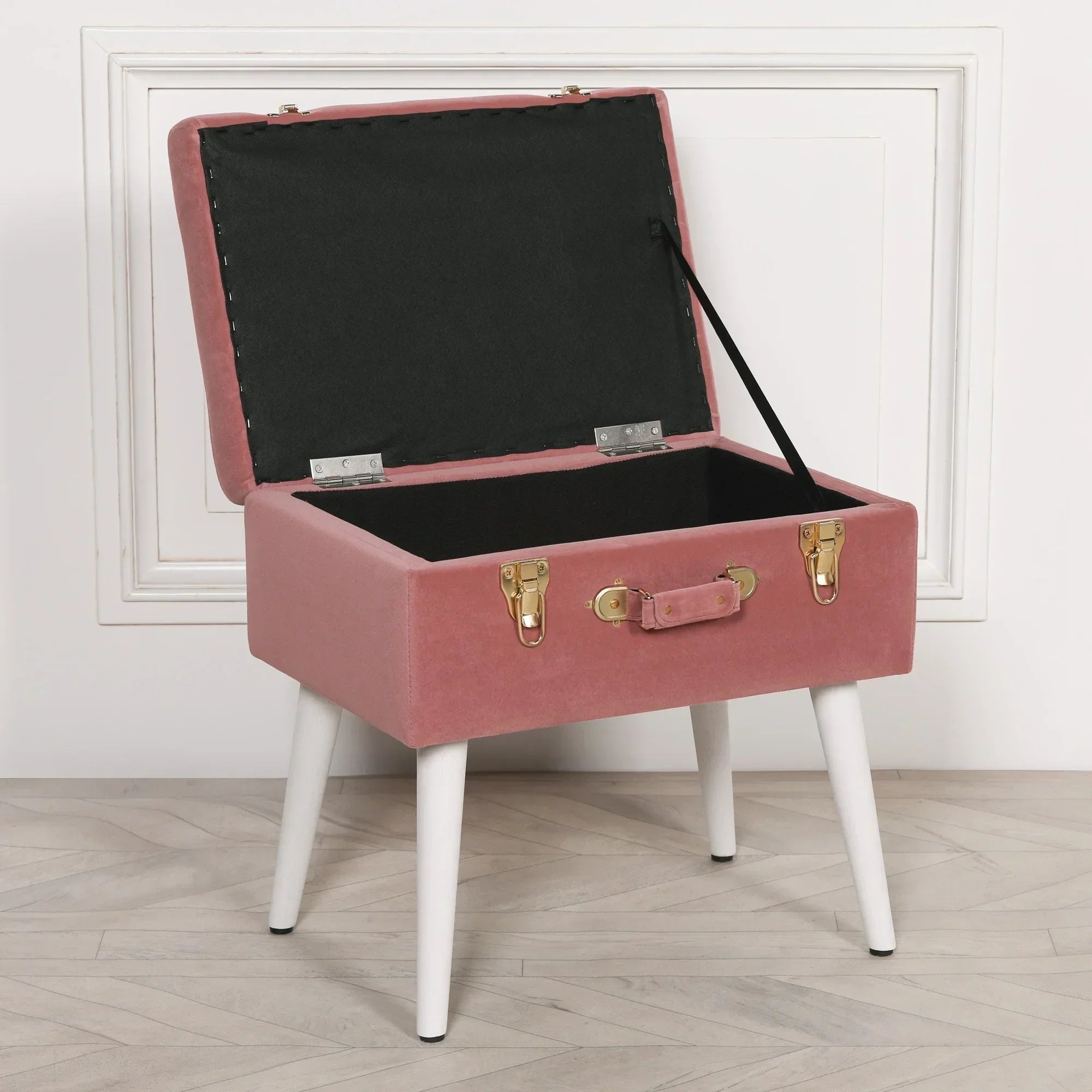 Pink velvet storage trunk ottoman with open lid and white tapered wooden legs