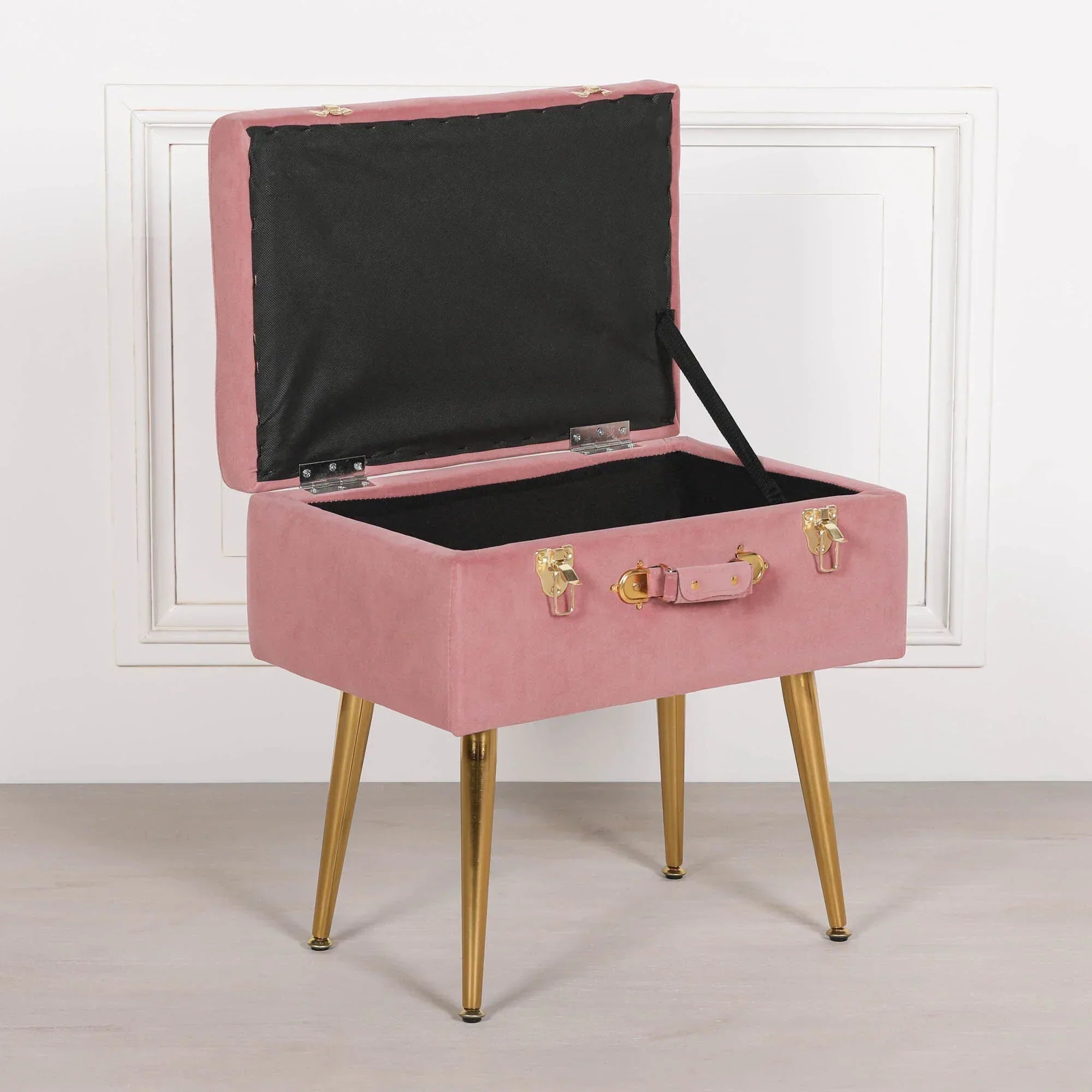 Pink velvet storage stool with gold legs and suitcase-style handle, lid open
