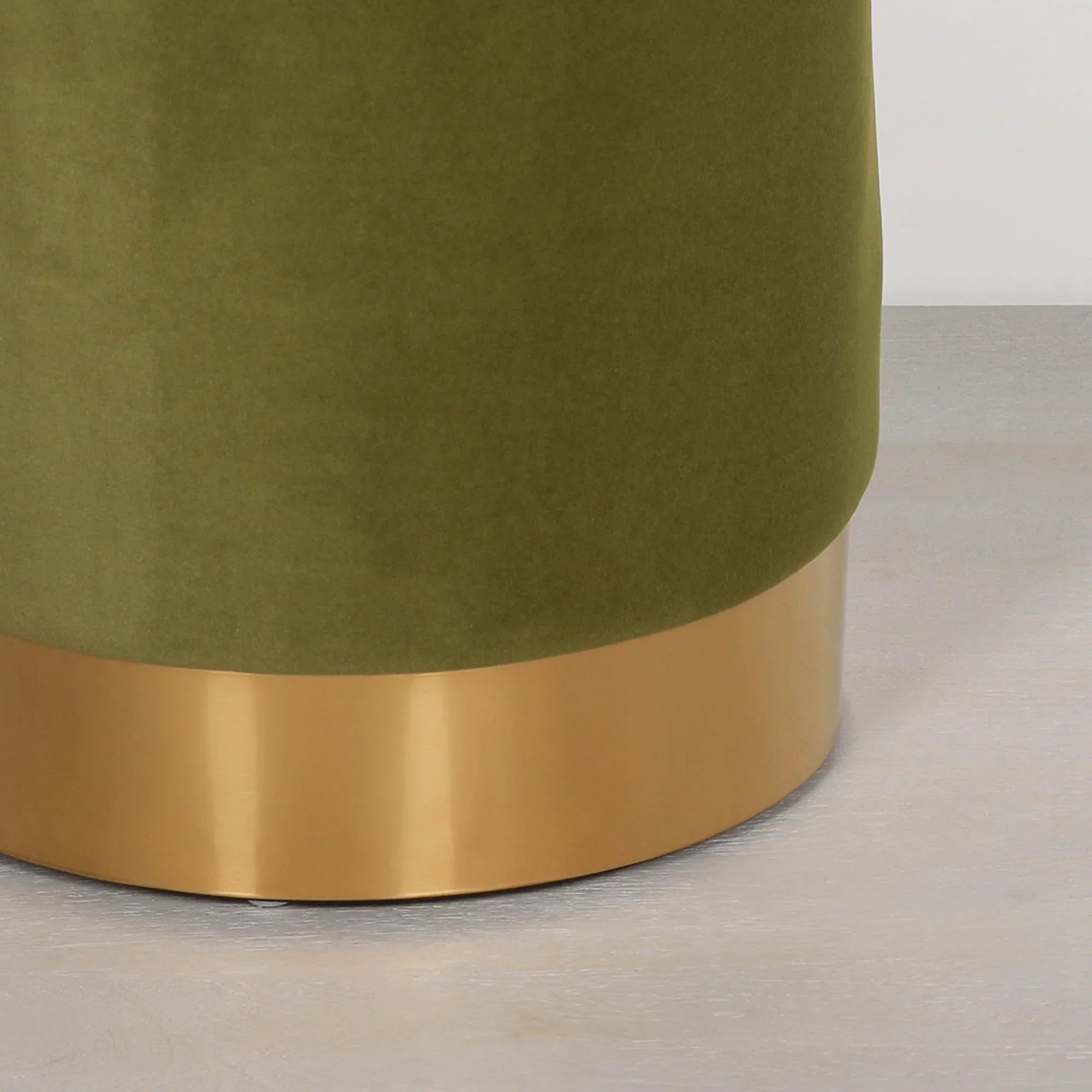 Green velvet ottoman with gold metal base on light wood floor
