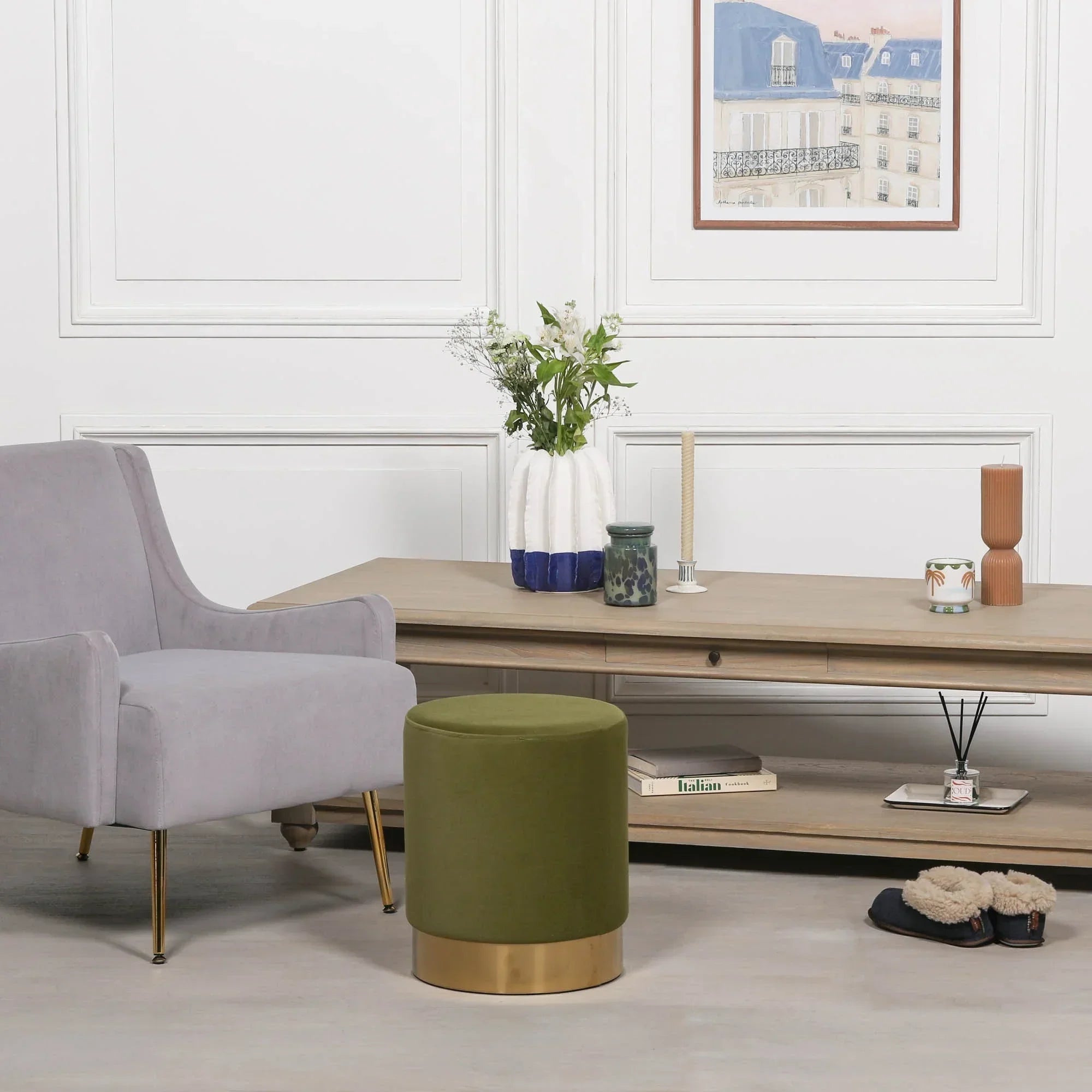 Olive green velvet footstool with gold base in modern living room next to grey armchair