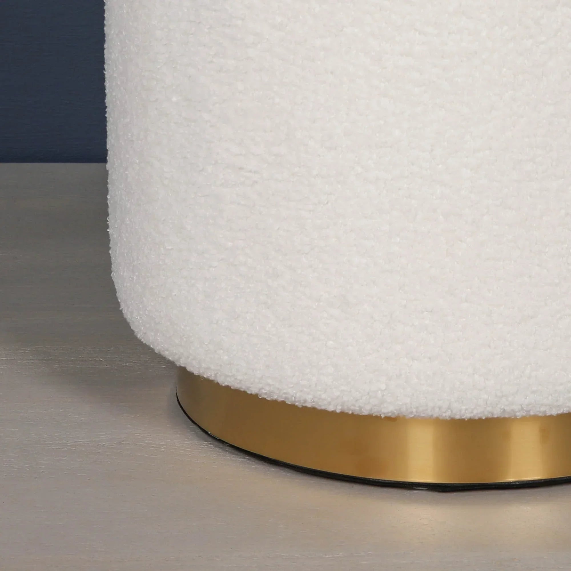 White boucle stool with gold metal base on light wood floor