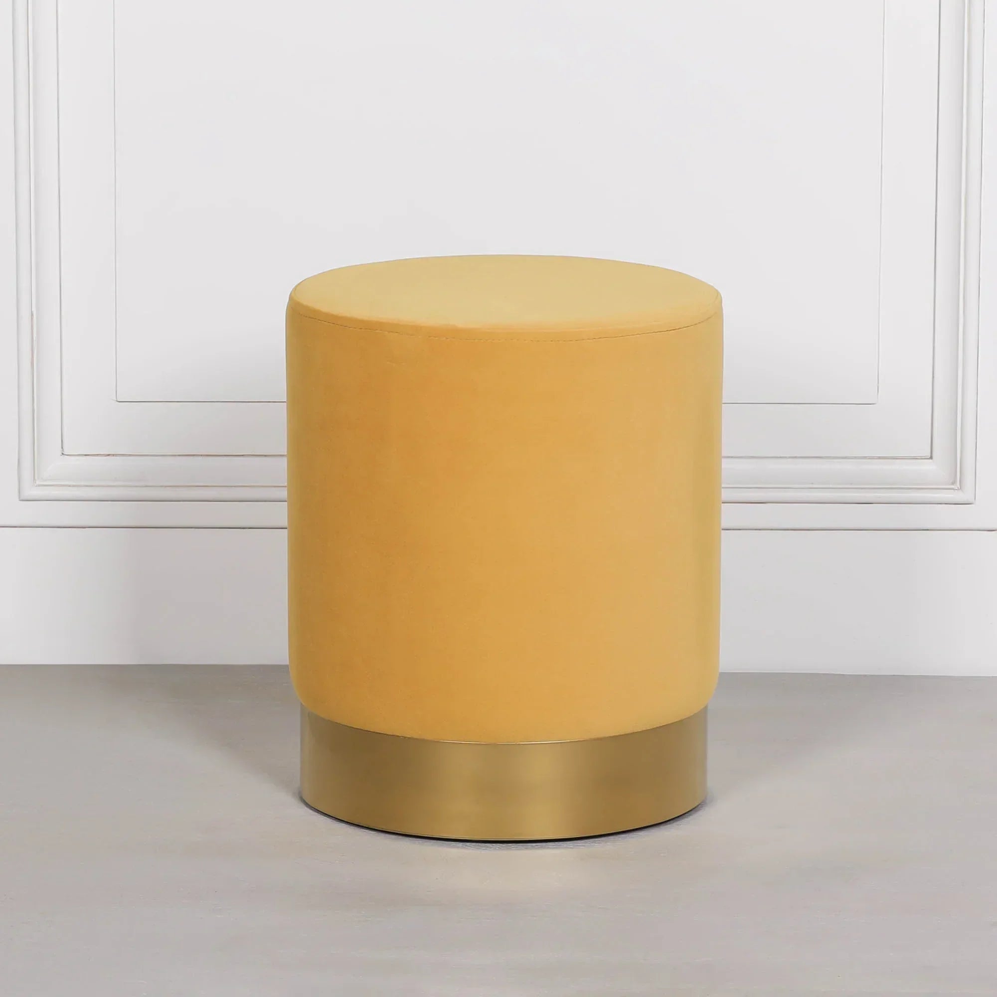 Yellow velvet round stool with gold metal base on grey floor