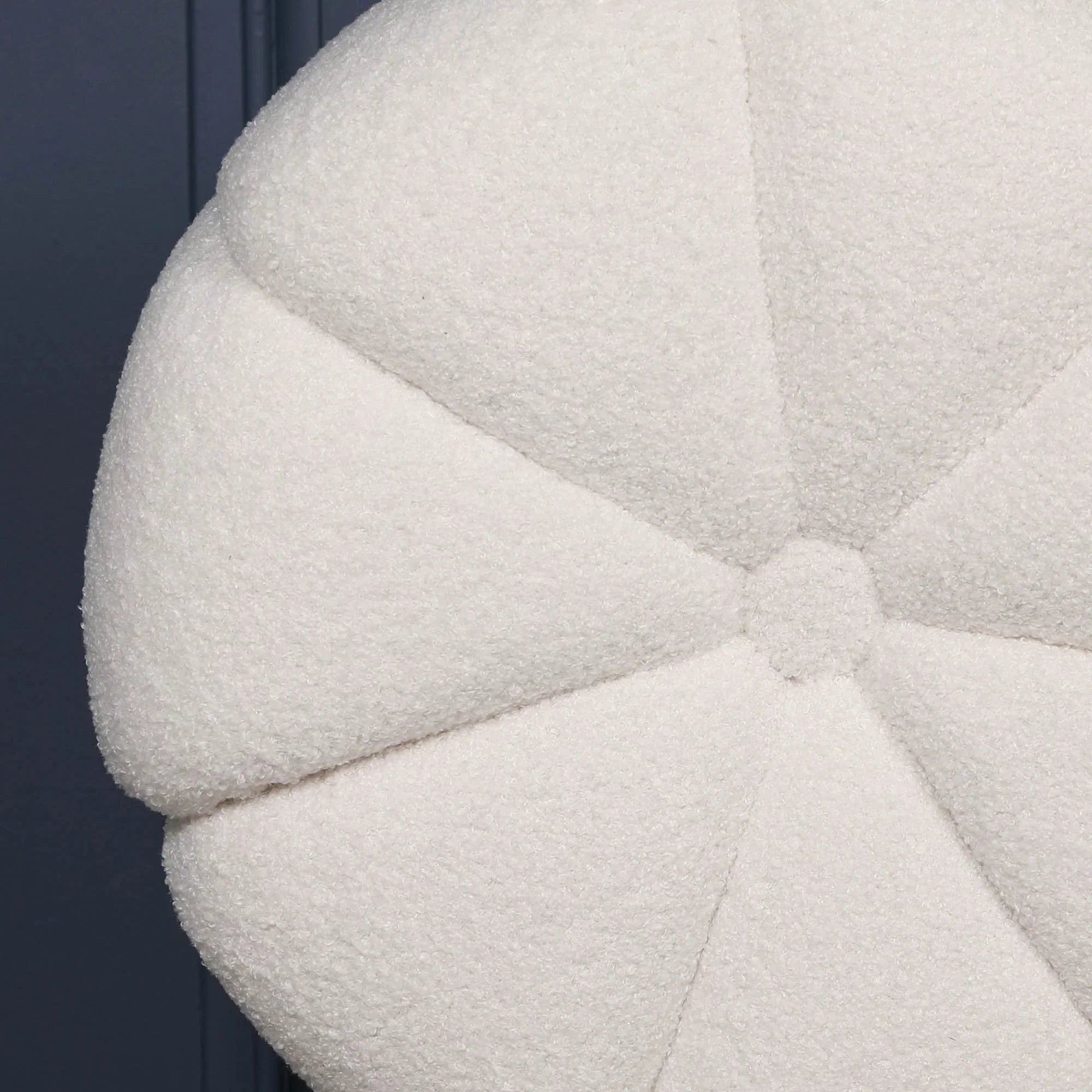 Close view of round white boucle cushion with stitched panel detailing