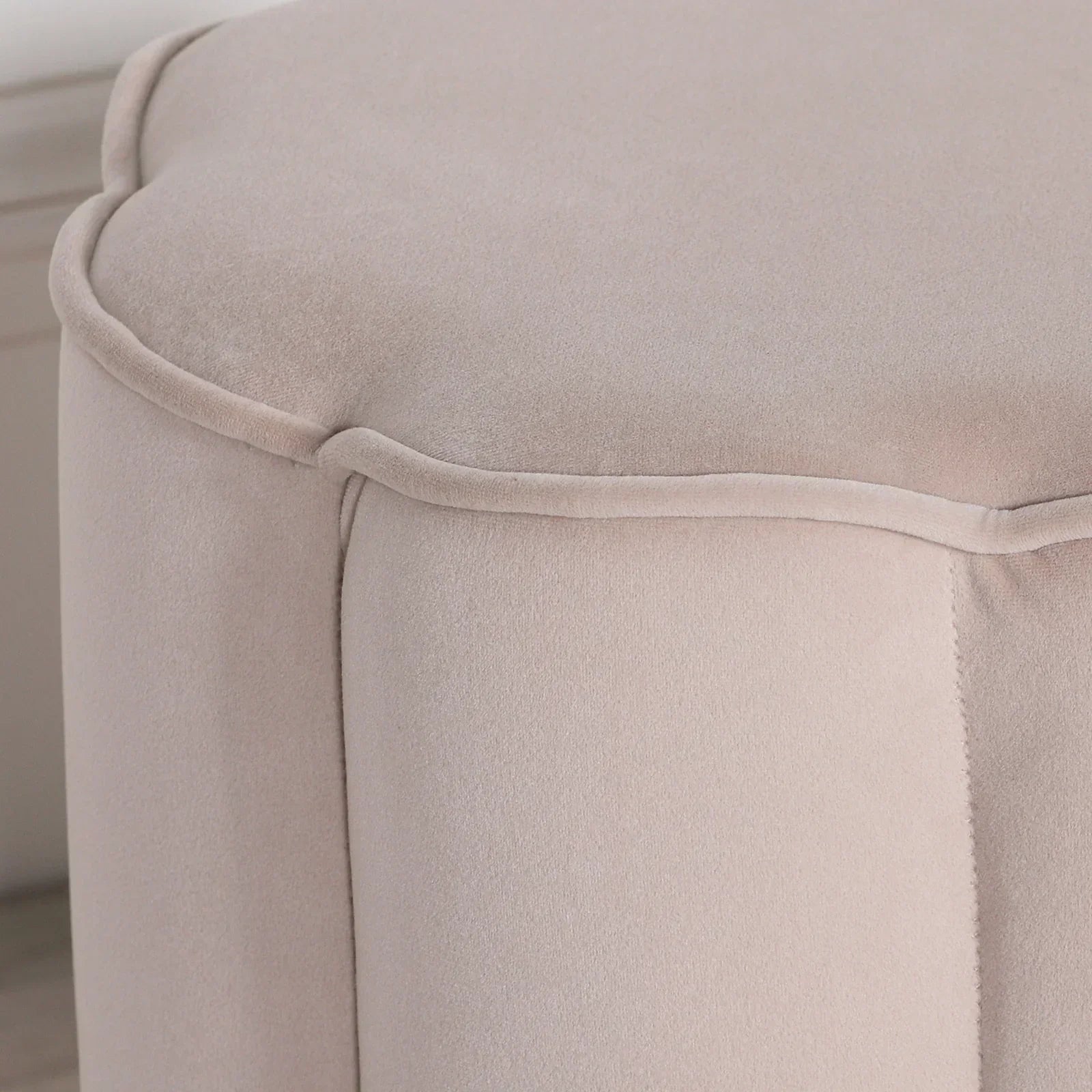 Beige velvet ottoman with piped edge detail, close-up of textured upholstery
