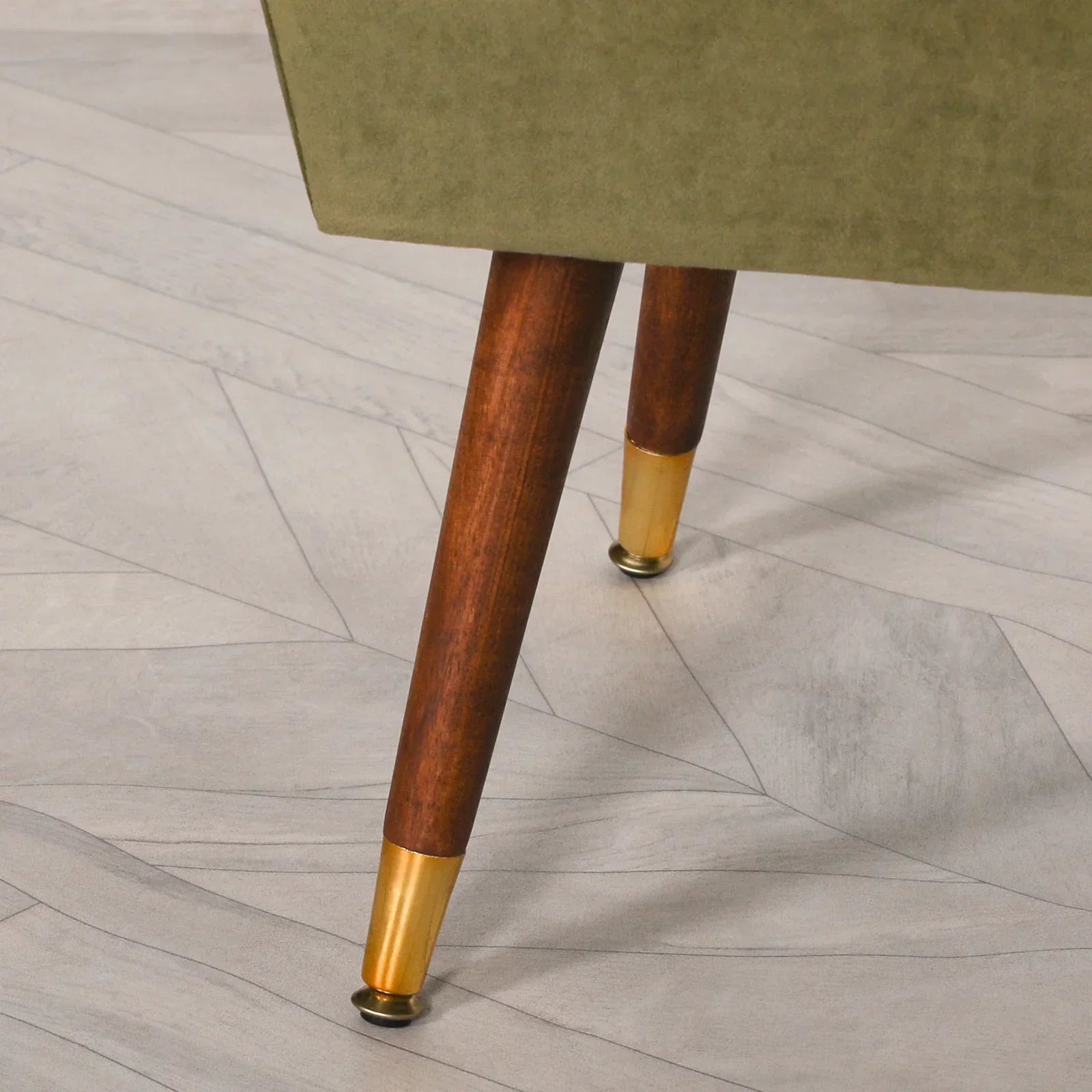 Closeup of sofa wooden legs with brass tips on light patterned flooring