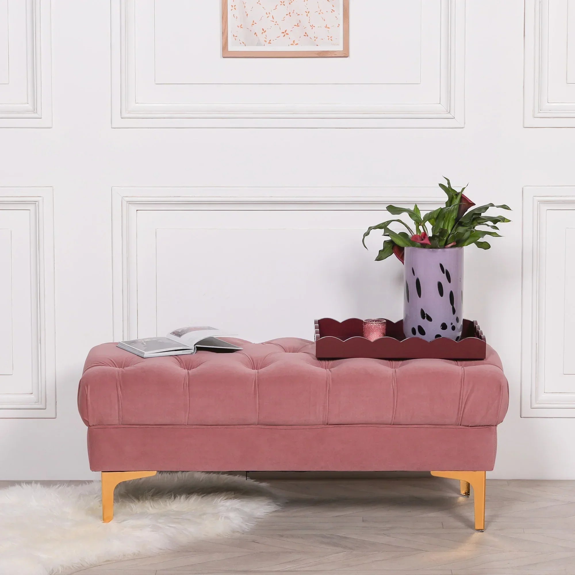 Pink velvet ottoman bench with tufted cushion, gold legs, tray and plant in modern room