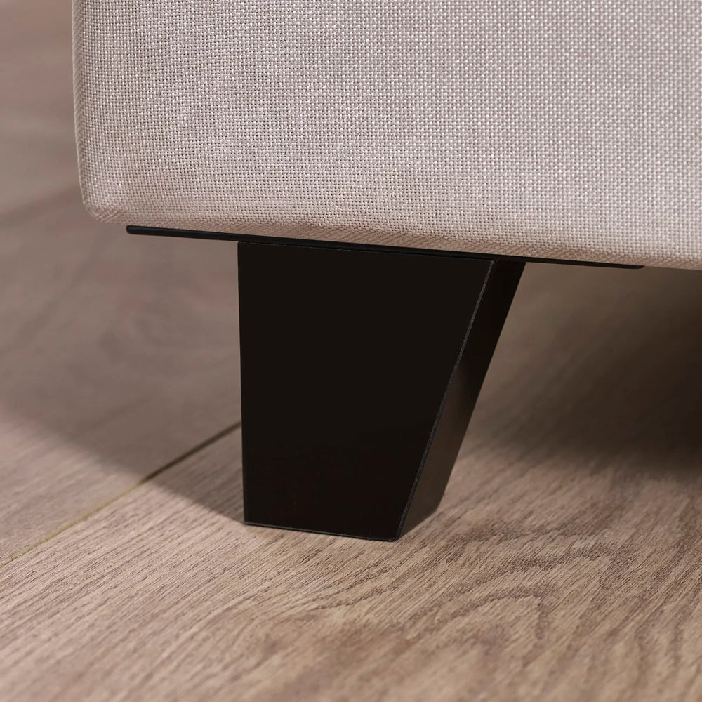 Closeup of fabric sofa corner with black metal leg on light wood floor