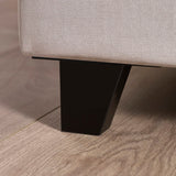 Closeup of fabric sofa corner with black metal leg on light wood floor