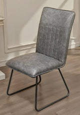 Grey faux leather dining chair with metal sled legs on wood floor