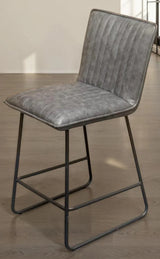 Grey counter bar stool with padded seat, vertical stitching and black metal legs on wood floor