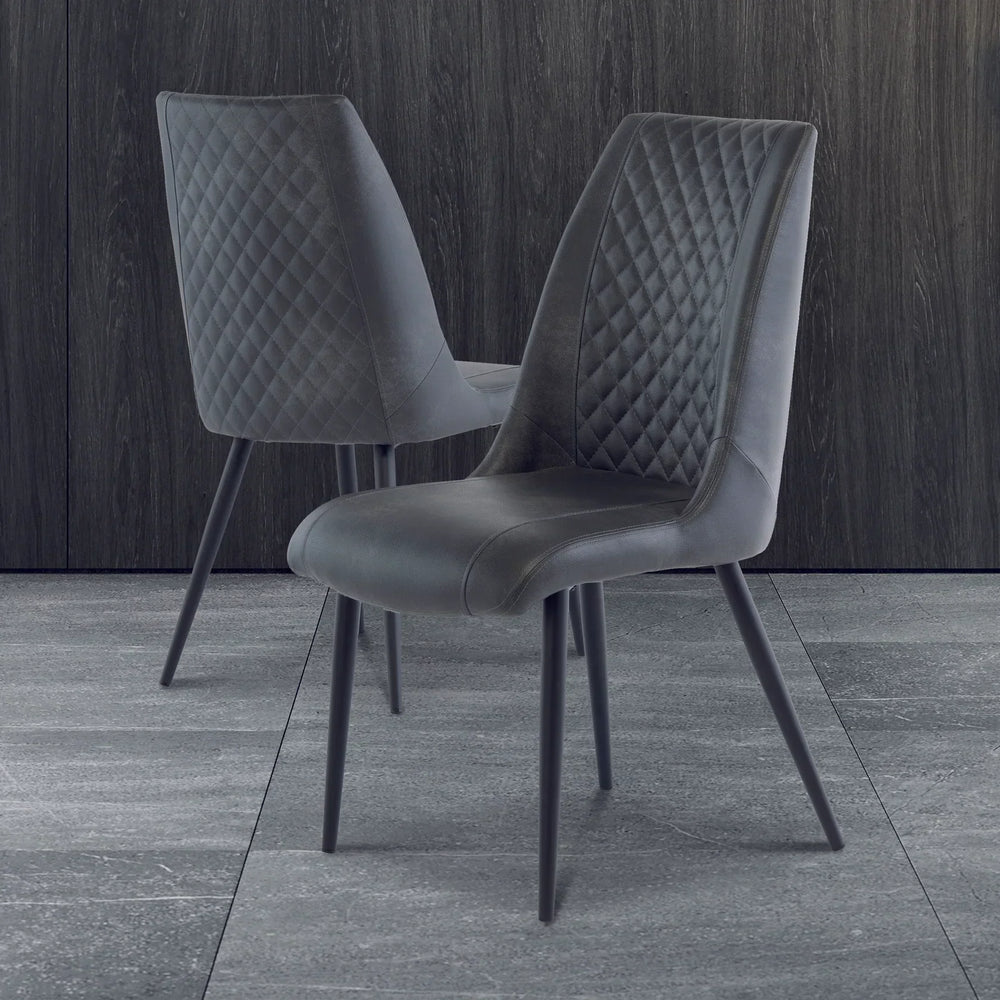 Pair of grey velvet dining chairs with quilted backrest on modern tiled floor