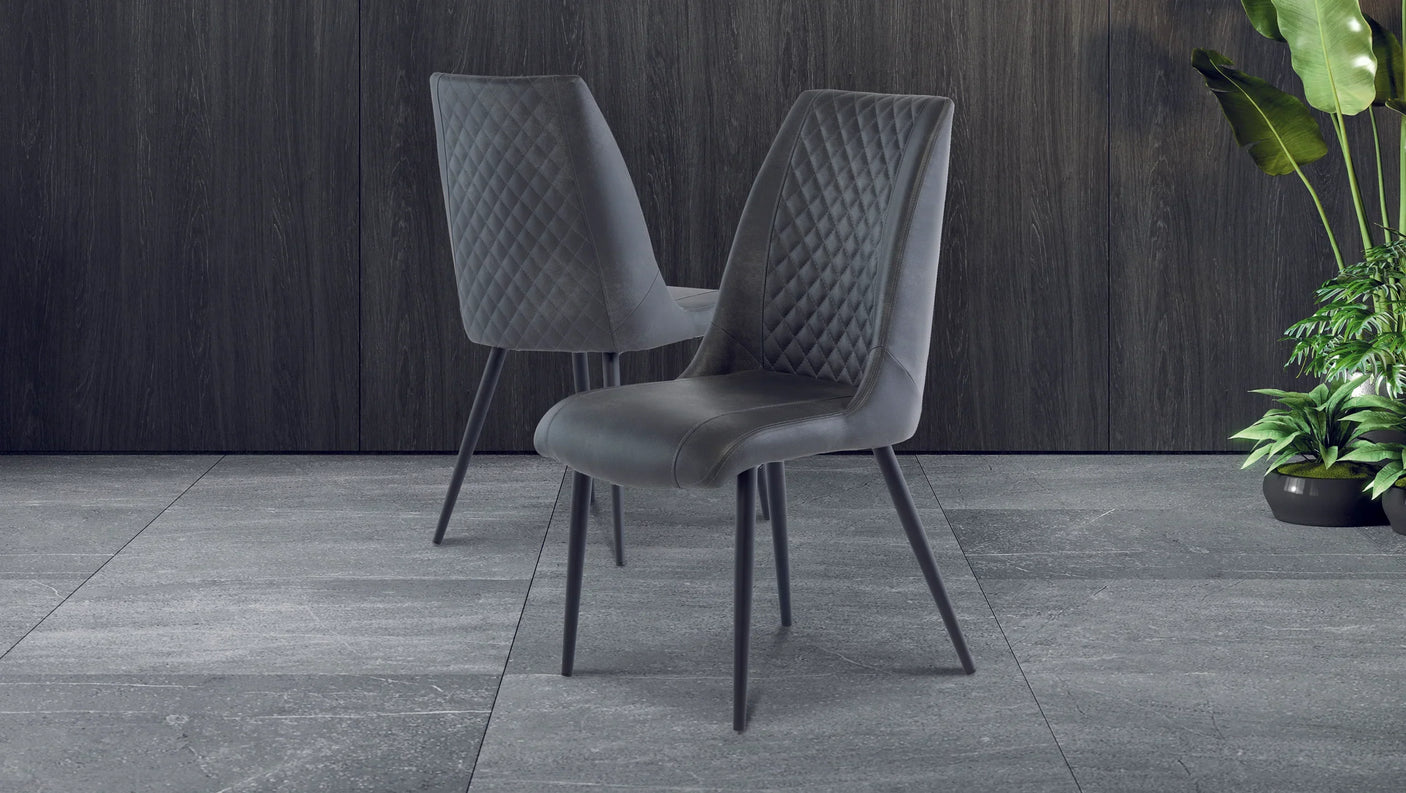Pair of grey velvet dining chairs with quilted backrest on modern tiled floor