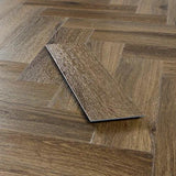 Antique walnut herringbone vinyl flooring sample on wood patterned floor