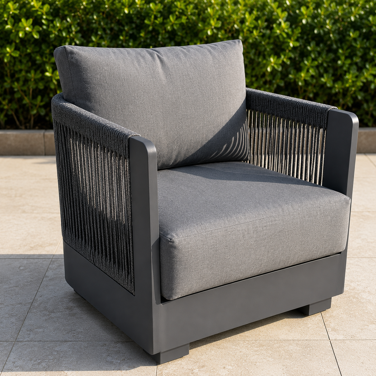 Grey fabric cushion with black rope sides and matte black metal frame armchair on patio tiles