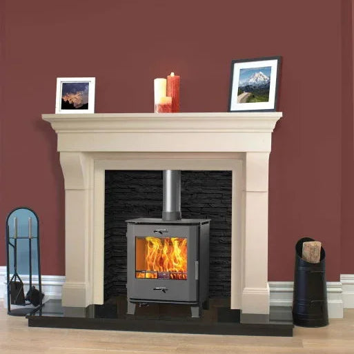 Cream fireplace with wood burning stove, black stone surround, and accessories on hardwood floor