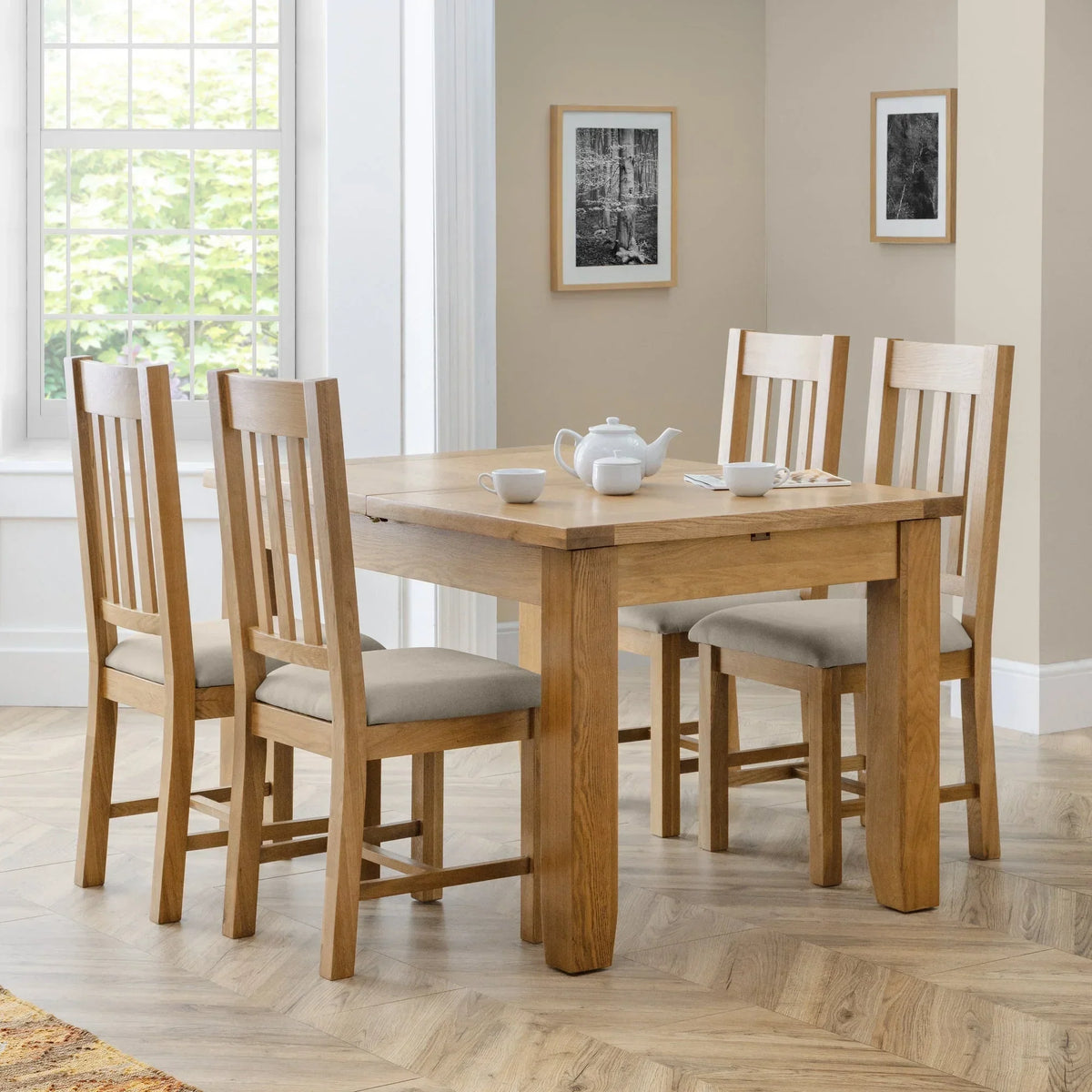 Oak dining table set with four beige upholstered chairs in a bright dining room