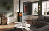 Modern living room featuring an Atlas wood burning stove with a warm fire, surrounded by stylish decor and natural light.