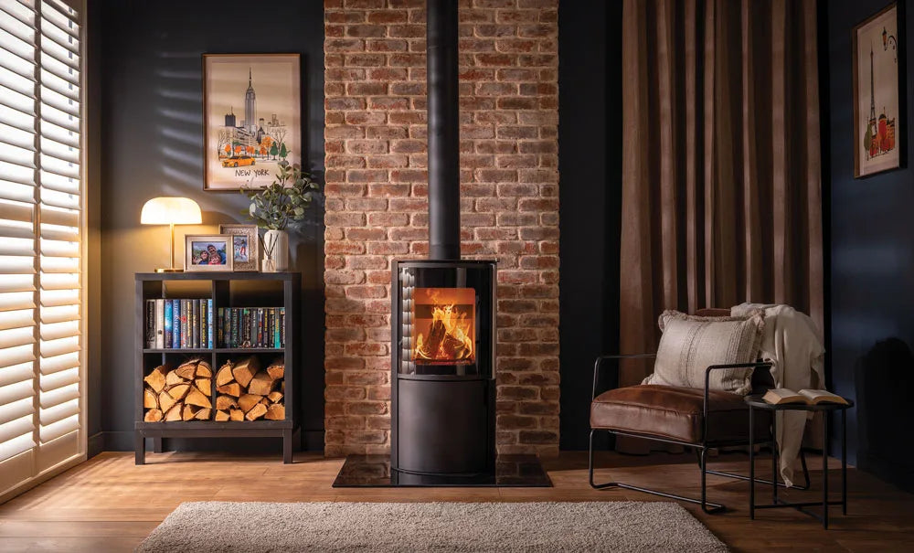 A modern Atlas wood burning stove in a stylish living room with a brick wall, wooden floor, and cozy seating.