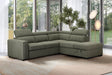 Green sectional sofa in a living room with large windows and plants.