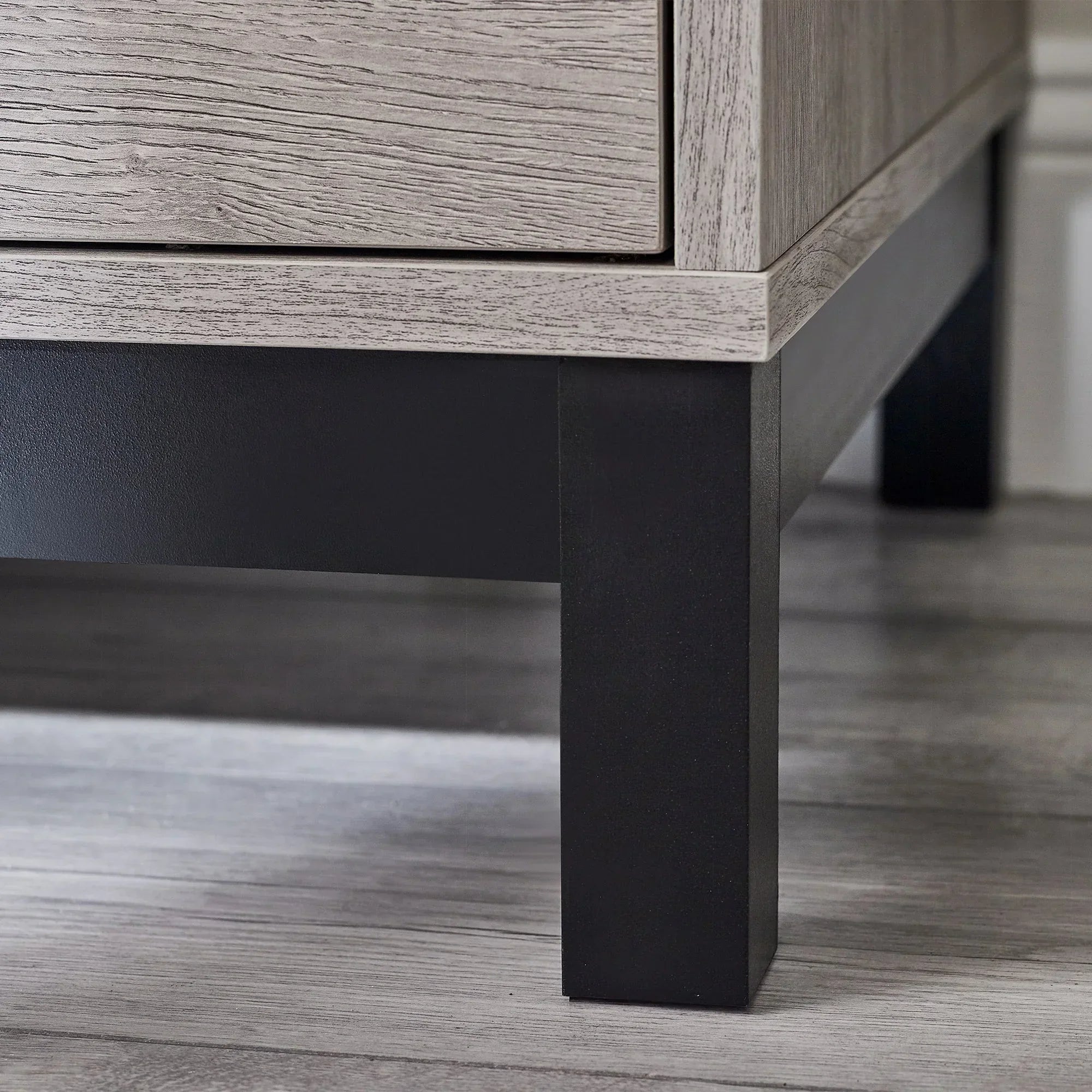 Wardrobe leg detail showing black metal frame and light oak wood finish on laminate flooring