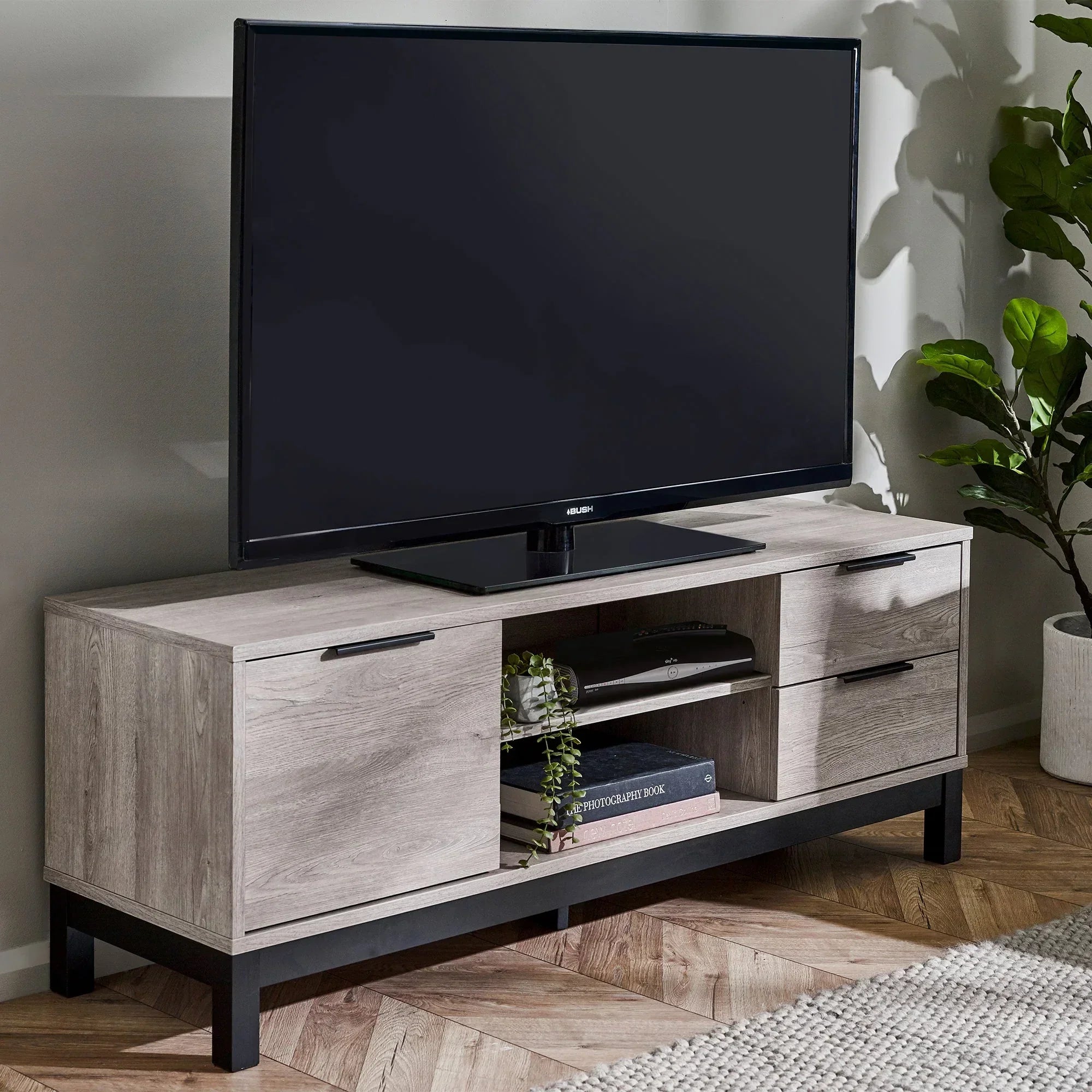 Grey oak TV unit with drawers and shelves, black handles, in modern living room setting