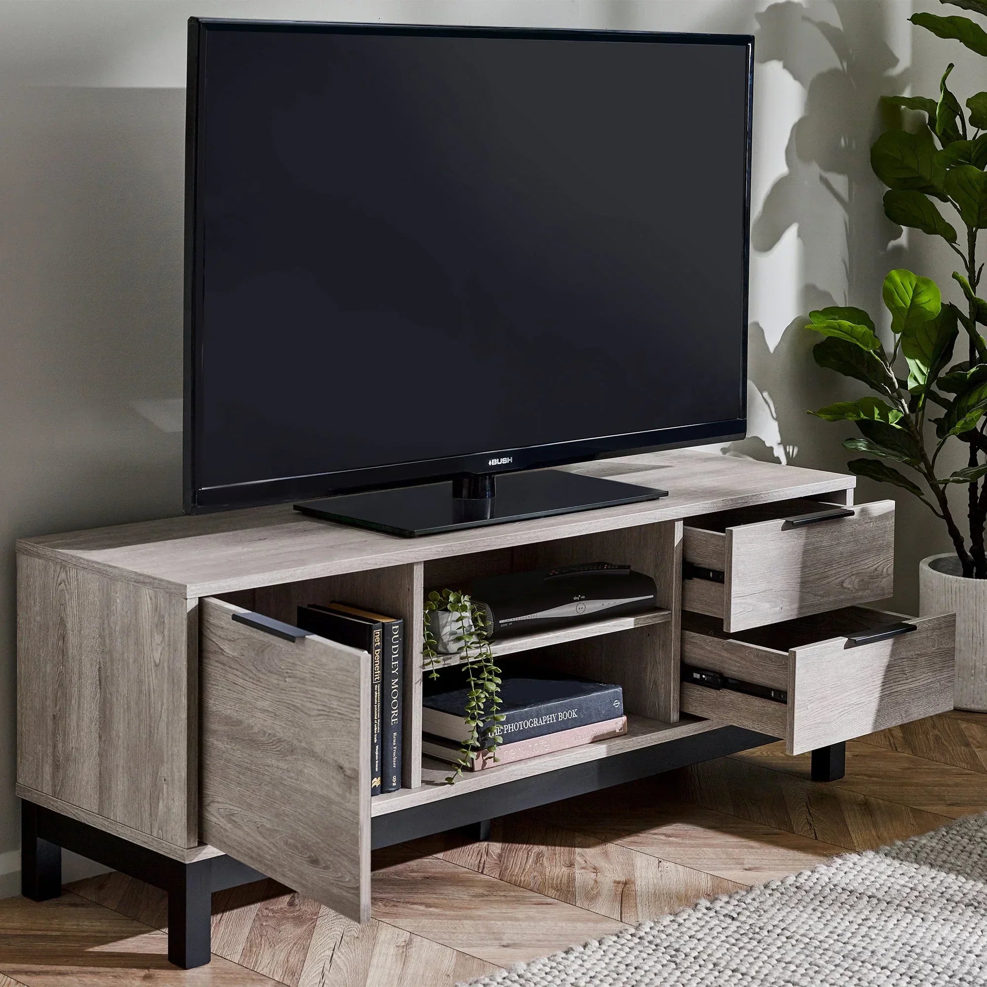 Grey oak TV unit with open doors and drawers, books and decor on shelves, living room setting
