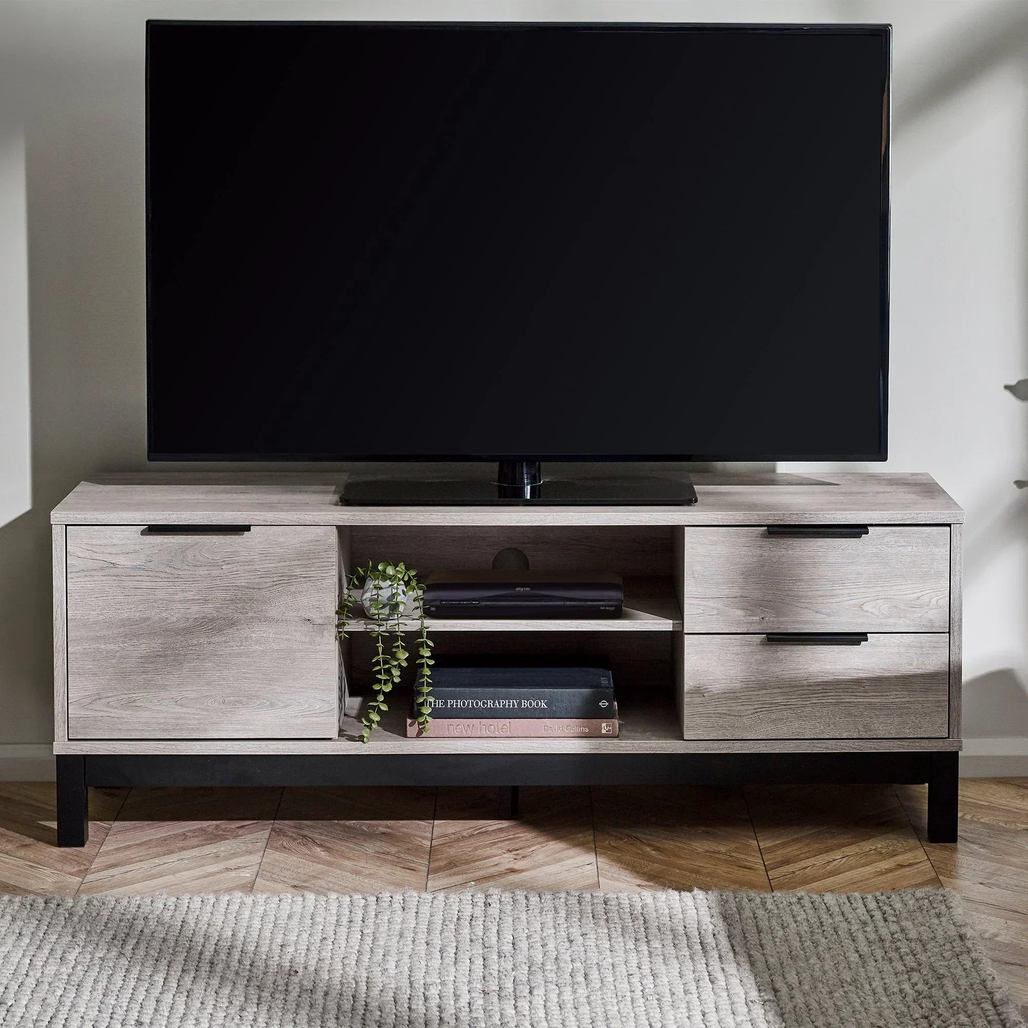 Grey oak TV unit with storage shelves and drawers, styled in a modern living room