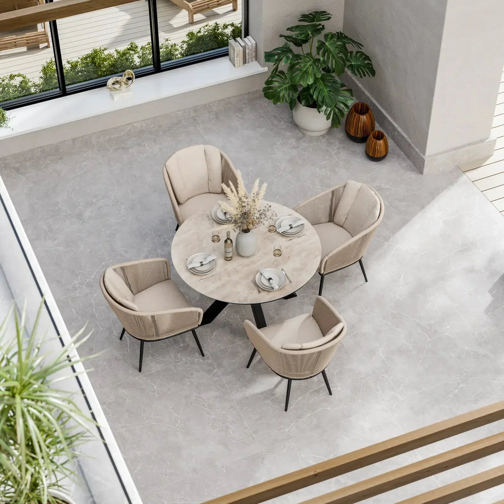 Round marble dining table with four beige upholstered chairs in modern sunroom