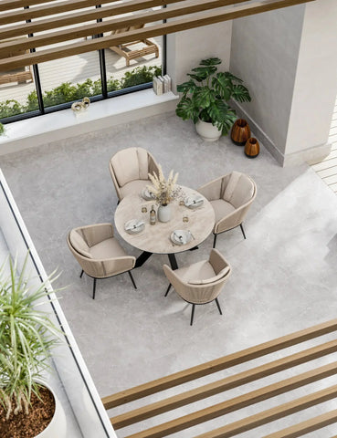 Round marble dining table with four beige upholstered chairs in modern sunroom