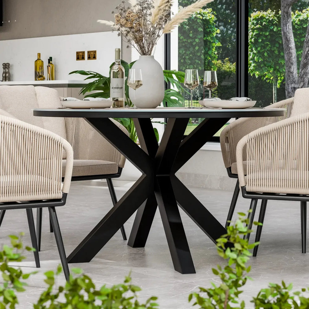 Modern round dining table with black metal base and rope chairs in bright dining room
