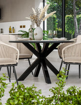 Modern round dining table with black metal base and rope chairs in bright dining room