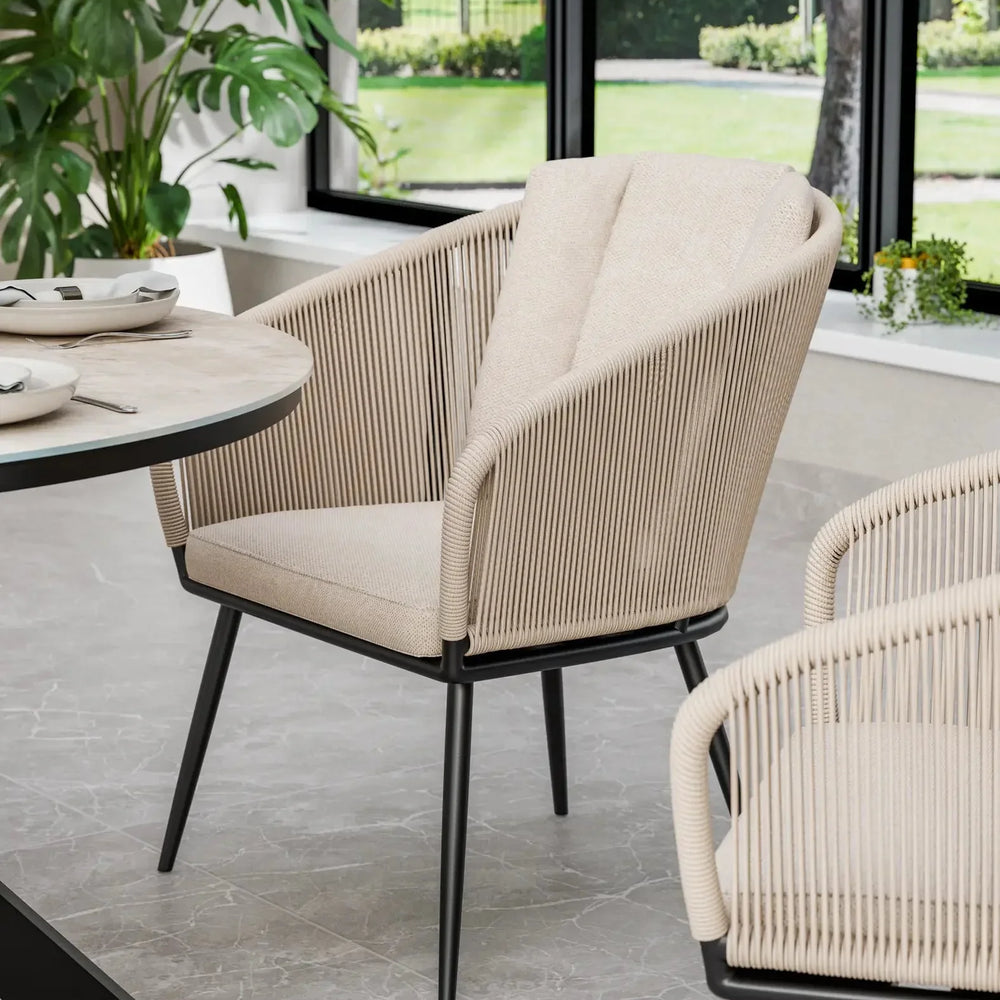 Beige rope dining chair with black legs beside modern round table in bright dining room