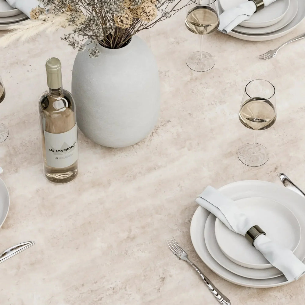 Ceramic dining table set with white plates, wine glasses, cutlery and a flower vase
