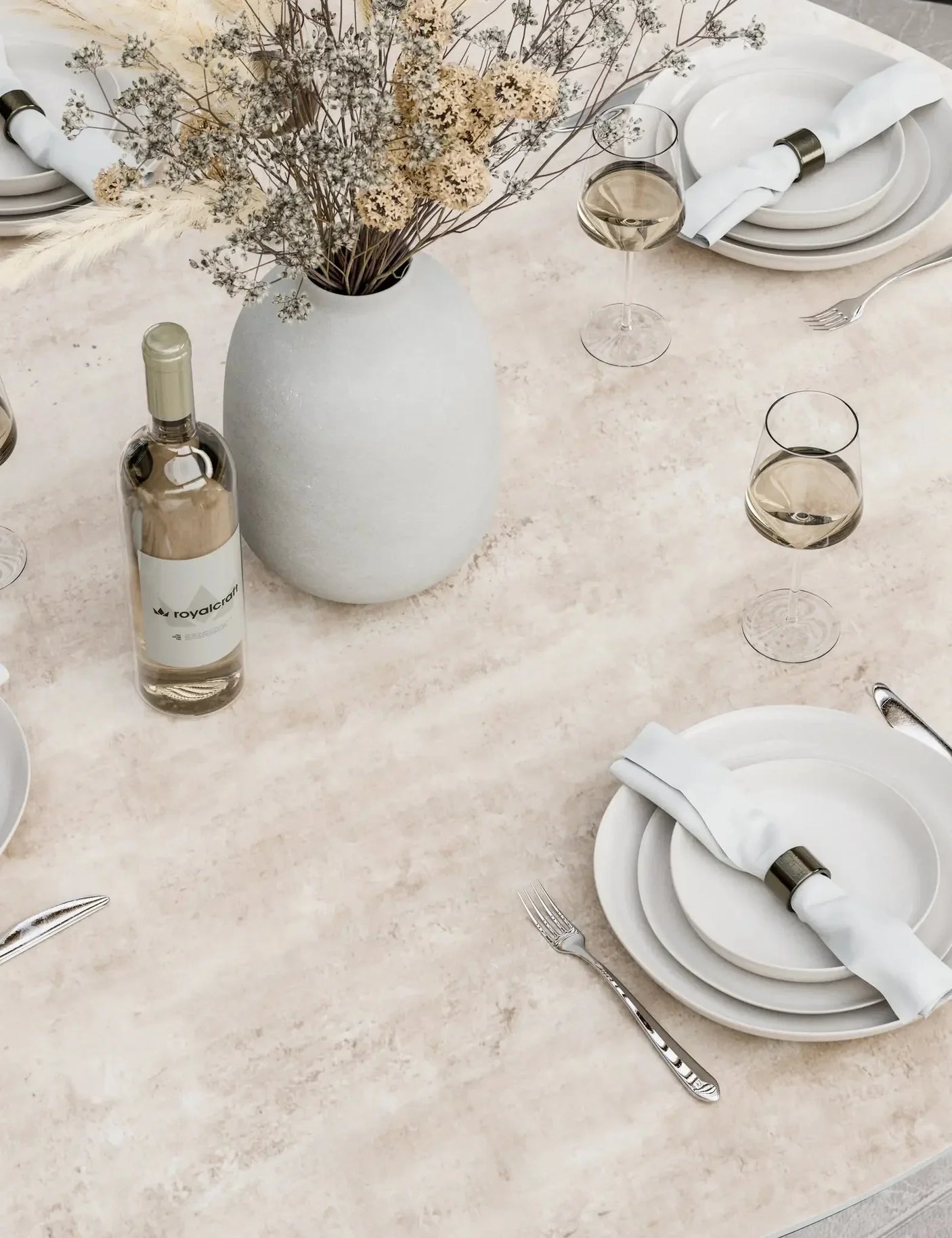 Ceramic dining table set with white plates, wine glasses, cutlery and a flower vase